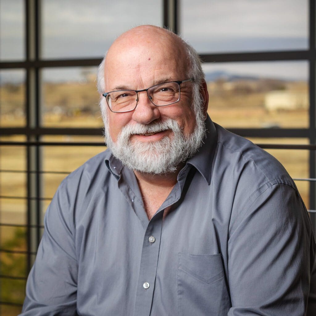 A man with glasses and a beard sitting in front of a window, representing Fann Contracting.