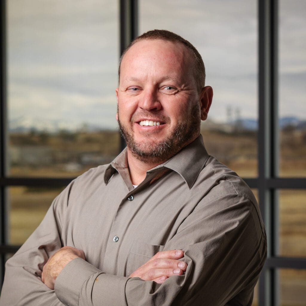 A man with his arms crossed in front of a window, representing Fann Contracting.