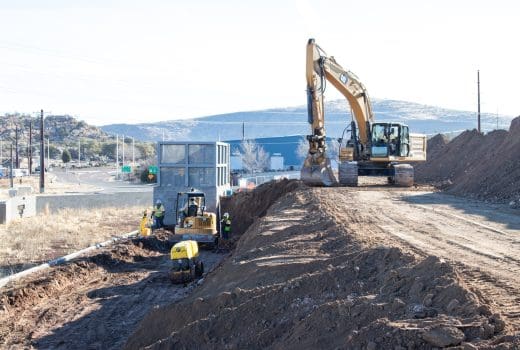 An excavator is working on a dirt road.